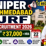 NIPER Ahmedabad JRF Recruitment 2026 thumbnail featuring NIPER Ahmedabad campus, a young researcher, salary ₹37,000 + HRA, application deadline of 22 June, and recruitment announcement graphics.
